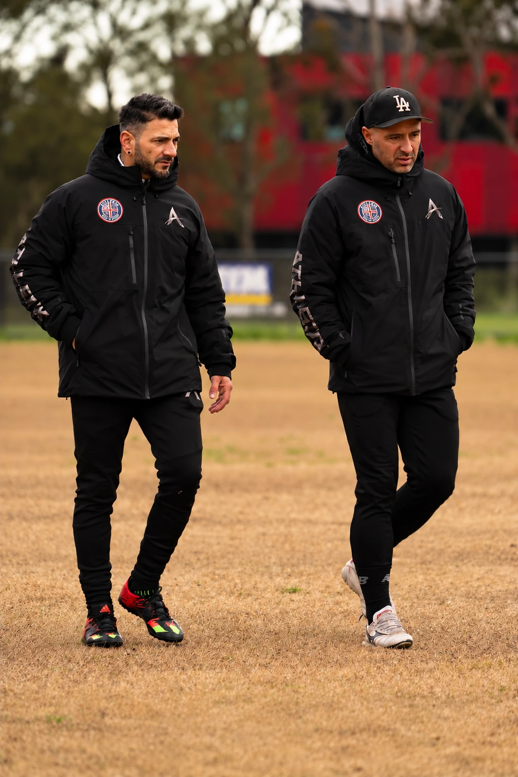 Two ATHLETIX coaches walking together on the football pitch